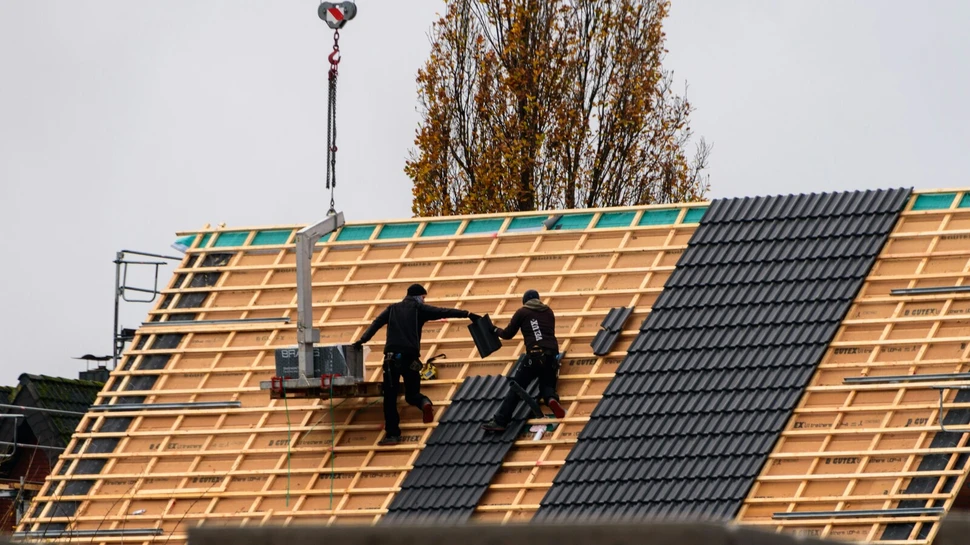 Zwei Handwerker decken ein Dach