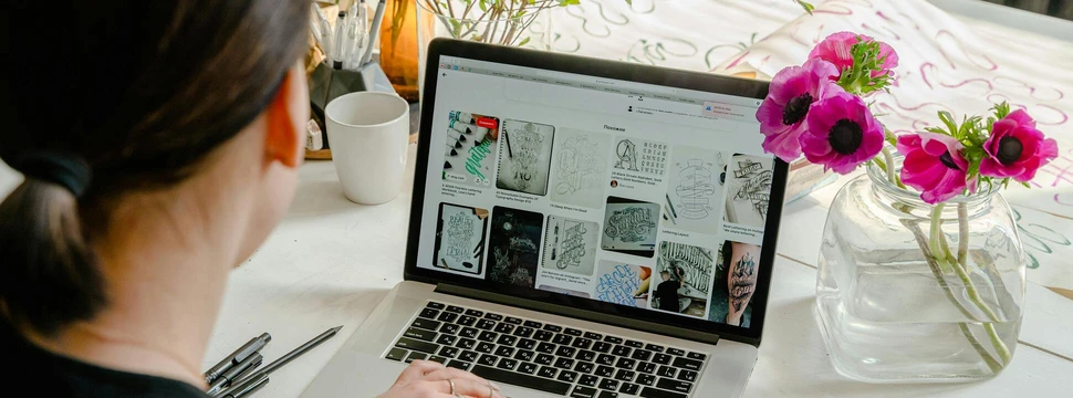 Eine Frau an einem Laptop mit einer Tasse Kaffee daneben beim Erstellen einer Website