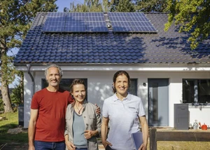 zwei Frauen und ein Mann stehen vor einem weißen Haus