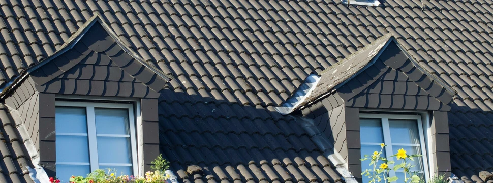 Hausdach mit zwei Gauben und braunen Dachziegeln