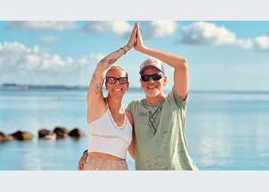 Frau und Mann bei Yoga am Strand von Scharbeutz und Haffkrug an der Ostsee in einer Yogaübung vor dem Meer