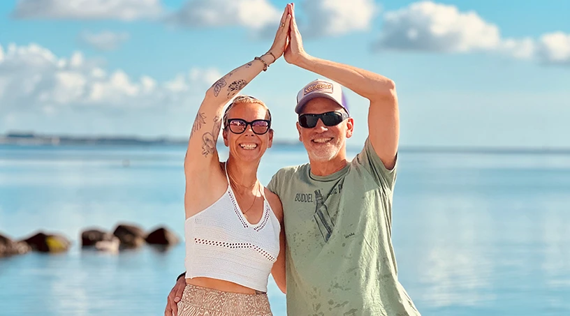 Frau und Mann bei Yoga am Strand von Scharbeutz und Haffkrug an der Ostsee in einer Yogaübung vor dem Meer