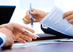 Hände von zwei Personen mit Stift und Papier