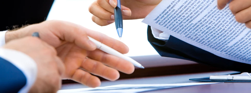 Hände von zwei Personen mit Stift und Papier